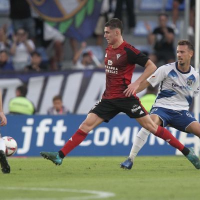 Jugador del CD Mirandés da un pase entre dos jugadores blanquiazules (CD Mirándes)