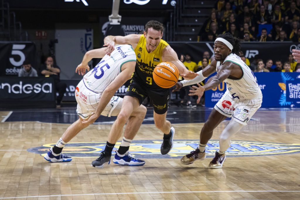 Marcelinho Huertas intenta zafarse de la defensa de Unicaja (ACB Media)